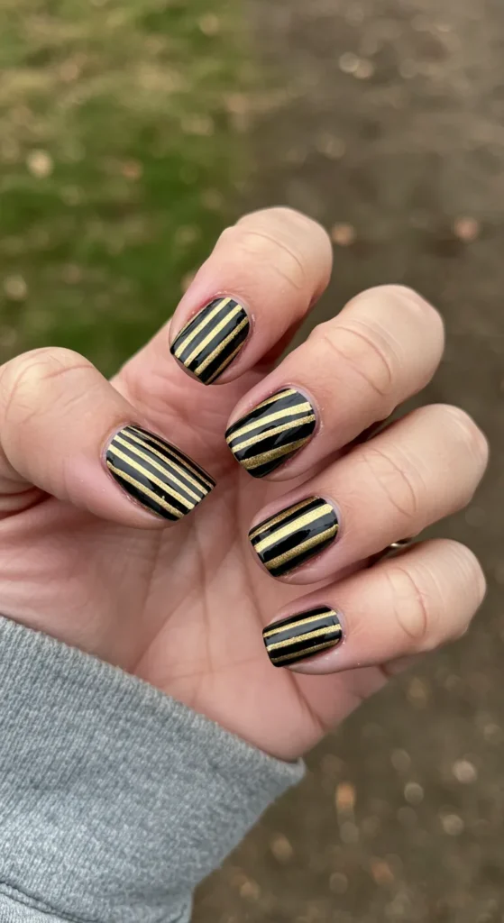 Bold black or gold stripes crisscrossing each nail, with varying angles and widths for a dynamic, stylish look. ✨

