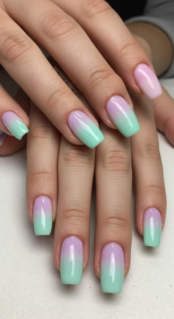 A close-up of pastel ombre nails fading from pale pink to light lavender and mint green, perfect for a soft spring look.